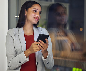 Image showing Thinking, phone and smiling woman texting, browsing the internet or using a mobile app with good network while working late at night. Hardworking entrepreneur checking investment growth online