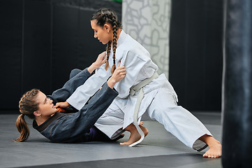 Image showing Mma, karate and jiu jitsu with two female athletes practicing, training and sparring in fight class. Healthy, fit and active women in gi or uniform learning self defense for safety and health