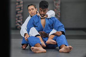 Image showing Woman in karate fitness training class with coach, learning self defence in gym class and fighting male trainer at fight club. Man teaching a student martial arts, foot control and rear naked choke