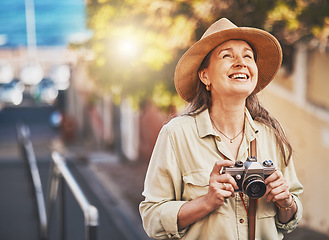 Image showing Happy photographer tourist taking photo of historic building with camera, smiling and carefree. Excited mature female solo travel journey, enjoying retirement while looking at bucket list destination