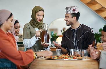 Image showing Group of muslim people celebrating Eid or Ramadan with iftar at home with food, drink and family. Young Islam woman pouring juice for a happy, smiling and positive man while breaking fast together