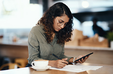 Image showing Small business owner or entrepreneur filling out paper work or a document in an internet cafe or coffee shop with a phone in hand. Young woman writing on a from and sitting at a table in a restaurant