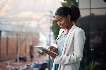 Image showing Business woman on a digital tablet outside a modern office alone. Smiling corporate worker looking at web and social media posts on a balcony. Female employee on a touchscreen device with copy space.