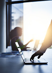 Image showing Silhouette of the hand of a businessman working on a laptop in an office with sunlight and a blurred shadow of a woman in the background with bokeh. Outline of a male brainstorming in the office.