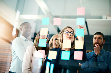 Image showing Group of business people talking about the notes on the glass wall in the office. Corporate meeting and discussion with the team about new ideas. Brainstorming logistics and strategy together.