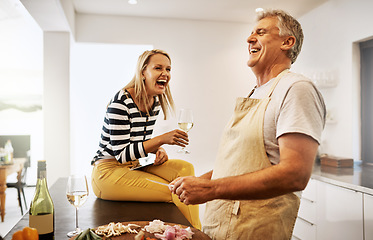 Image showing Happy and carefree couple cooking dinner laughing and enjoying the weekend in the kitchen at home. A mature husband relaxing and preparing a meal or lunch for his wife while having fun