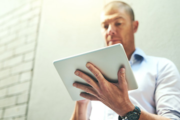 Image showing Businessman working on a tablet, reading quick email message online or checking company SEO website data while waiting outside. Mature corporate professional browsing internet on wireless technology