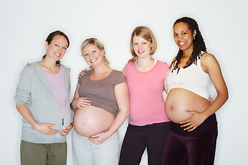 Image showing Pregnant, mother and friends with women in studio against a white background feeling happy with a smile. Pregnancy, health and wellness with positive female parents holding their abdomen together