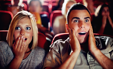 Image showing Couple watch a scary, horror or thriller movie in a cinema together and are shocked, wow or surprised. Man and woman in theatre on a date with omgand scared emotion or fear while watching a film