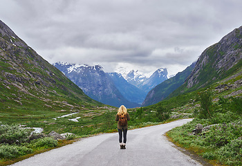 Image showing Adventure backpacking woman travels on road in epic majestic mountain snow landscape