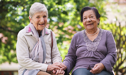 Image showing Two elderly women sitting on bench in park holding hands smiling happy life long friends enjoying retirement