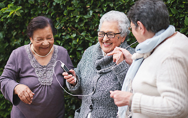 Image showing Happy old women listening to music on smartphone wearing earphones smiling enjoying fun celebrating retirement together outdoors