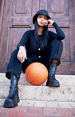 Image showing Basketball, fashion and model influencer of a woman posing on steps in an urban city with fashionable style. Female portrait of trendy, stylish and cool person in sports promotion for ball game.