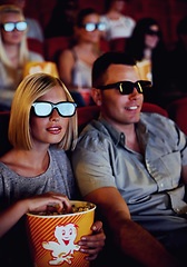 Image showing Couple watch a movie together in a cinema with 3D glasses while eating popcorn or a snack. Young man and woman sitting watching an action movies or film for entertainment during a date in a theatre