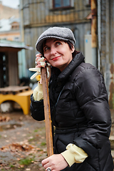 Image showing A woman diligently maintains the garden by collecting old, dry leaves, creating a picturesque scene of outdoor care and seasonal tidiness