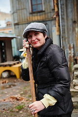 Image showing A woman diligently maintains the garden by collecting old, dry leaves, creating a picturesque scene of outdoor care and seasonal tidiness