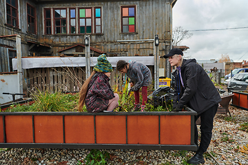 Image showing A modern family parents and children, is working together to beautify their front yard with flowers in preparation for the upcoming holiday season.