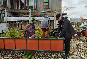 Image showing A modern family parents and children, is working together to beautify their front yard with flowers in preparation for the upcoming holiday season.