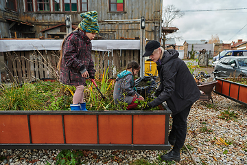 Image showing A modern family parents and children, is working together to beautify their front yard with flowers in preparation for the upcoming holiday season.