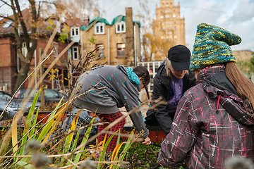 Image showing A modern family parents and children, is working together to beautify their front yard with flowers in preparation for the upcoming holiday season.