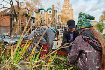 Image showing A modern family parents and children, is working together to beautify their front yard with flowers in preparation for the upcoming holiday season.