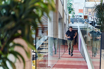 Image showing In the hustle and bustle of a modern startup office, a determined businessman sprints towards his office, embodying the fast-paced, ambitious spirit of contemporary entrepreneurship