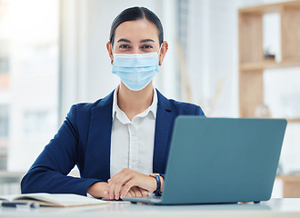 Image showing Compliance, face mask and covid rules at work with a business woman working on a laptop in a corporate office. Portrait of a female practice social distancing at workplace, regulations and hygiene