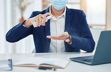 Image showing Businessman spray cleaning with a covid mask while working in an office. Entrepreneur cleaning and disinfecting his hands to prevent the spread of germs, corona and infection in the covid pandemic