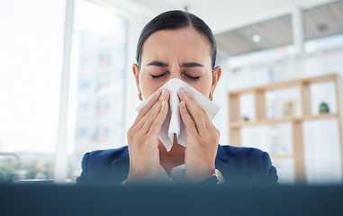 Image showing Covid, virus and sick with a business woman blowing her nose with a tissue and sneezing while working in her office. Allergies, sneeze and flu with a female employee suffering from a cold at work