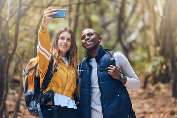 Image showing Hiking, diversity and couple taking a selfie with a phone while they smile, happy and travel in nature forest. Trekking, love and romance on adventure journey date with trees, earth and leaf growth