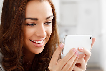 Image showing Happy woman watching videos with a phone with an internet app online to stream or download. Young lady smiling while reading a funny meme or enjoying a web series or movie with a smartphone at home