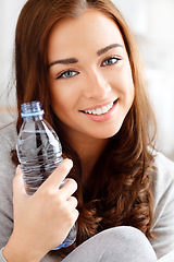 Image showing Face, beauty and water with a happy woman and a drink bottle in her home and giving a smile. Relax, skincare and teeth and a portrait of a lovely young female with hydration for glowing skin