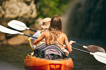 Image showing Women friends rowing a kayak or boat on a river or lake while on summer vacation or travel. Tourist explore nature on water during a tropical adventure kayaking in the a wildlife wilderness forest