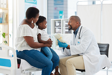 Image showing Doctor or pediatrician gives a teddy bear to a little girl after a medical appointment in a clinic with her mother. Small, happy child visiting the specialist for checkup in a healthcare hospital