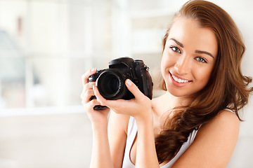 Image showing Photographer, digital camera and photography with a woman taking a photograph or picture inside. Portrait of a young female with a smile holding photo gear for a beauty shoot with a happy model