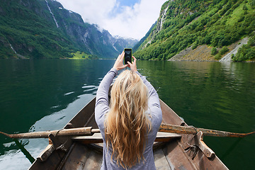 Image showing Adventure woman in row boat taking photo on smart phone of beautiful fjord lake for social media