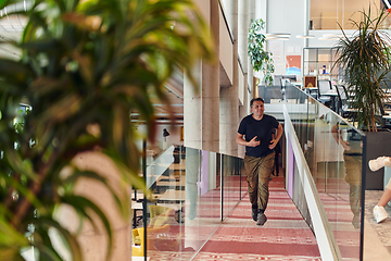 Image showing In the hustle and bustle of a modern startup office, a determined businessman sprints towards his office, embodying the fast-paced, ambitious spirit of contemporary entrepreneurship