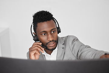 Image showing Call center, customer service and crm representative wearing headset while consulting with customer in telemarketing company. Serious black man in contact us and sales support working on a computer