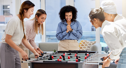 Image showing Team building, break and business women playing game in office lounge room having fun and bonding together. Trendy, cool and diversity of creative staff with fun mini table football match activity