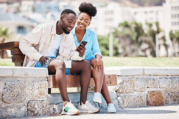Image showing Black couple, love and phone while browsing social media, internet or watching a video while sitting on a park bench. Happy man and woman on a romantic date, trip or summer holiday to relax together