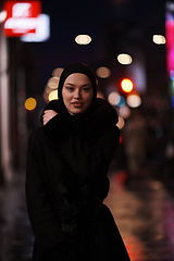 Image showing Muslim woman walking on urban city street on a cold winter night wearing hijab