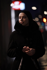 Image showing Muslim woman walking on urban city street on a cold winter night wearing hijab