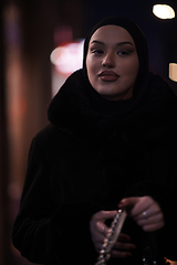 Image showing Muslim woman walking on urban city street on a cold winter night wearing hijab