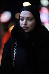 Image showing Muslim woman walking on an urban city street on a cold winter night wearing hijab