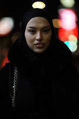 Image showing Muslim woman walking on an urban city street on a cold winter night wearing hijab