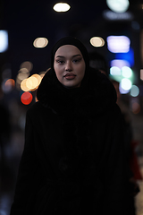 Image showing Muslim woman walking on an urban city street on a cold winter night wearing hijab