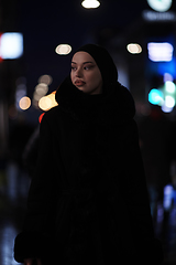 Image showing Muslim woman walking on an urban city street on a cold winter night wearing hijab