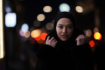 Image showing Muslim woman walking on urban city street on a cold winter night wearing hijab