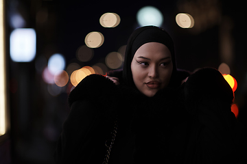 Image showing Muslim woman walking on urban city street on a cold winter night wearing hijab