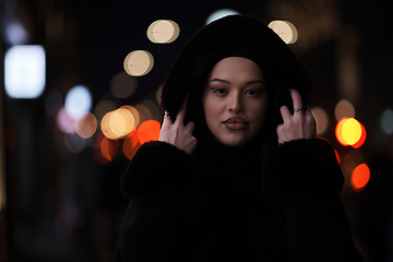 Image showing Muslim woman walking on urban city street on a cold winter night wearing hijab